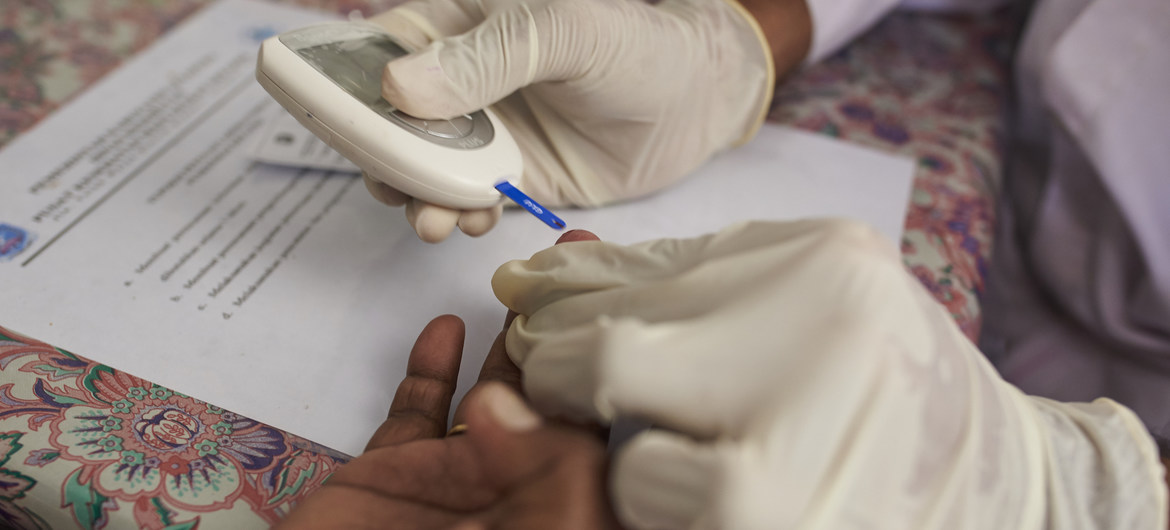  Um profissional de saúde verifica o nível de açúcar no sangue de uma mulher em um centro de saúde comunitário na Indonésia